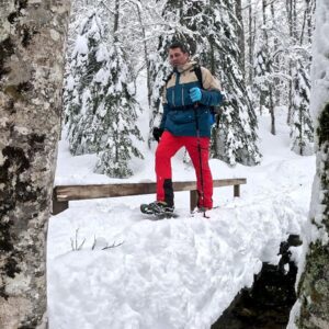 Participante camina con sus raquetas de nieve a través de un bosque nevado